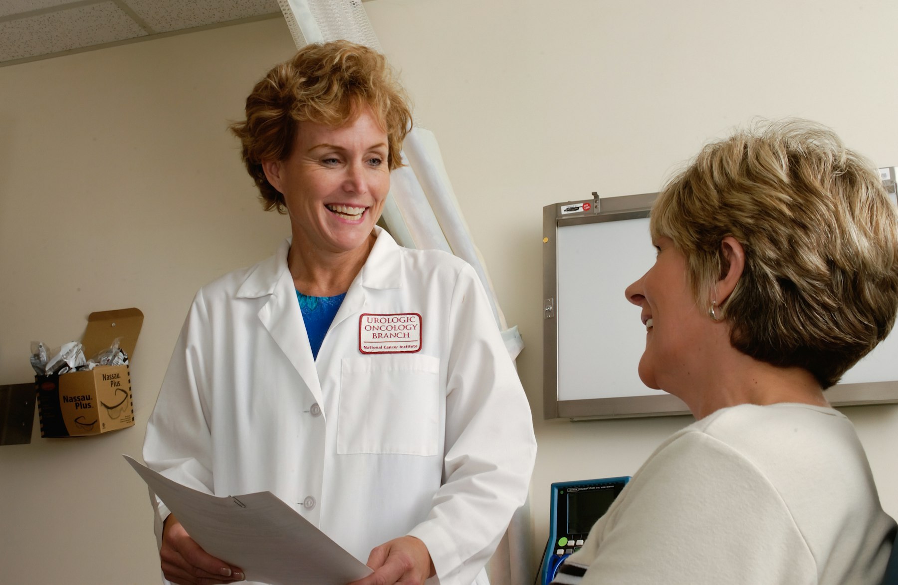 Médica sorrindo conversando com uma paciente no consultório
